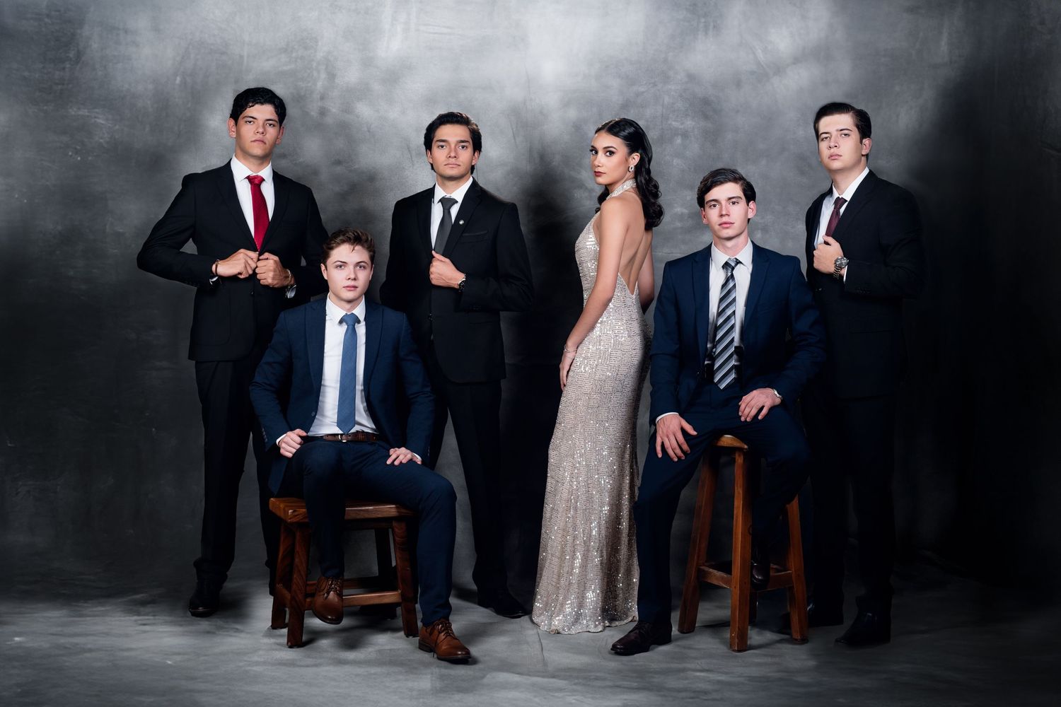 Group portrait session with formal attire against dark textured backdrop.