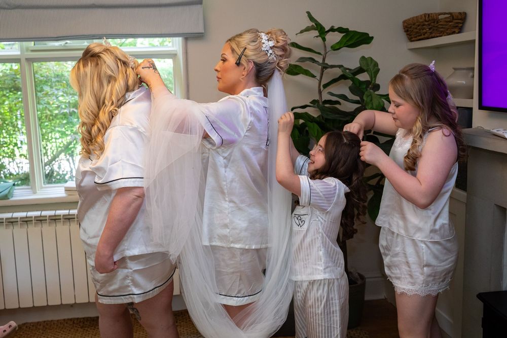 Bridesmaids helping bride adjust her veil and wedding dress before the ceremony.