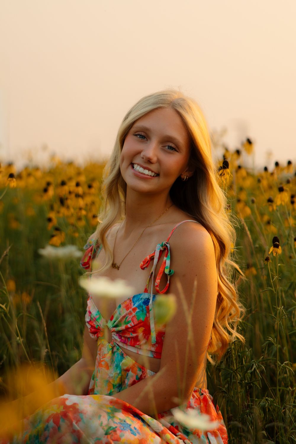 A floral sundress stands out against a golden field of sunflowers during sunset.
