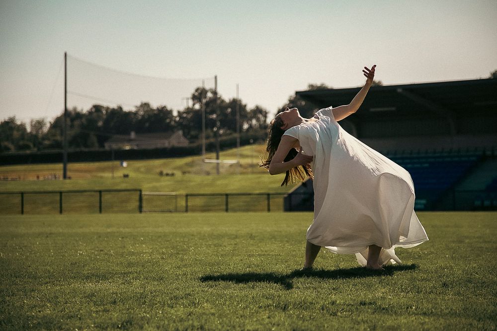 A goat leaps and plays joyfully in a sunny green pasture field.