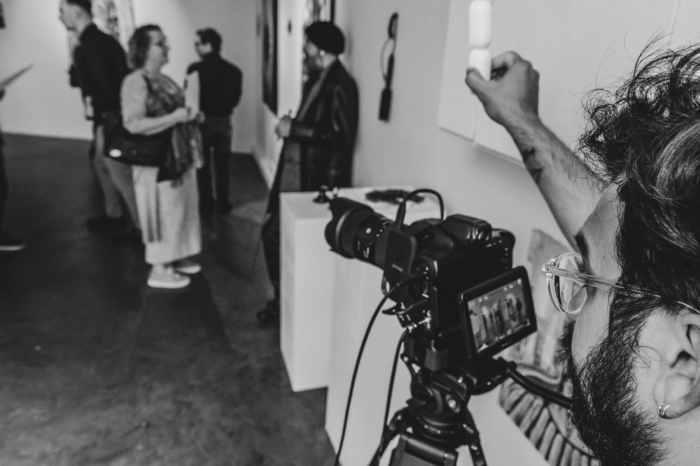 Behind-the-scenes film crew setting up equipment and cameras in a white studio space.