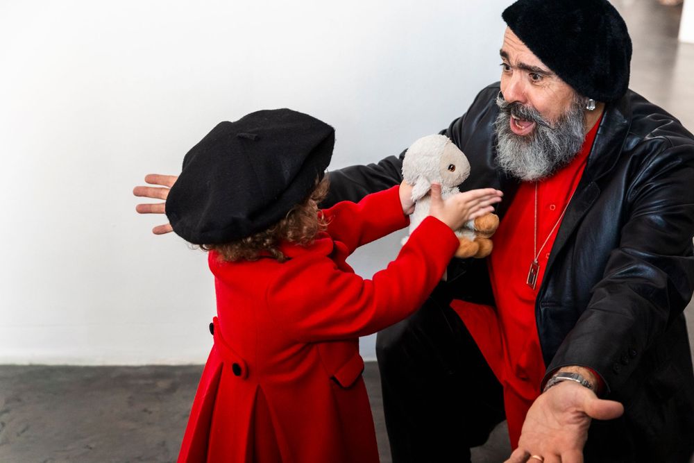 A sequence of four black and white photos showing two people in red and black outfits interacting and embracing.