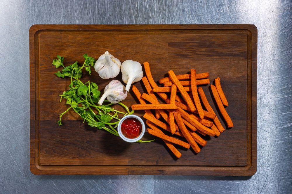 Fresh carrots, garlic, and herbs arranged on wooden serving boards in a progression sequence.