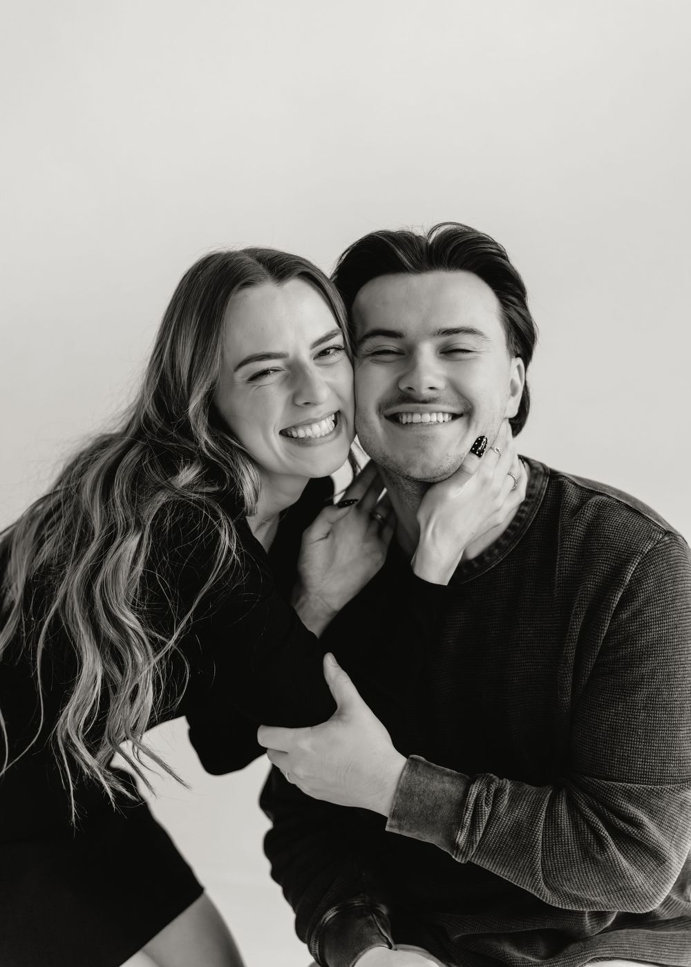 A couple in black clothing shares playful candid moments in a series of black and white photographs.