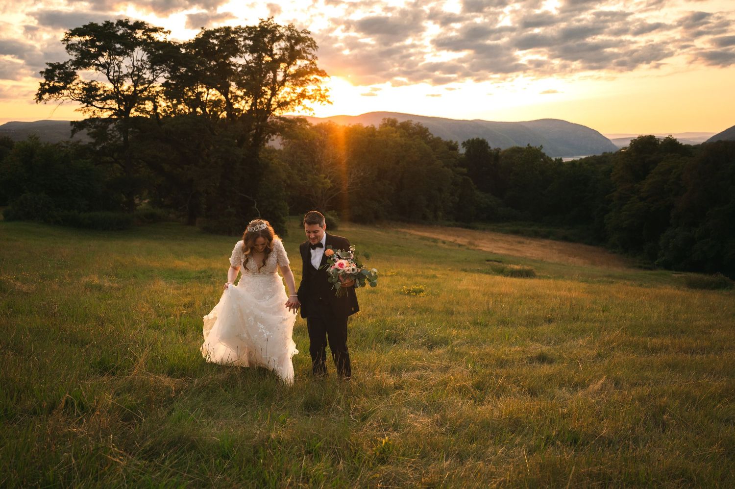 A couple shares a romantic sunset kiss at their wedding with mountains and Hudson River in the background of The Garrison in Garrison, NY.