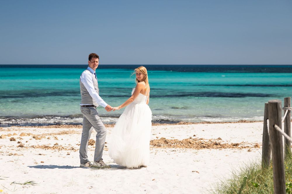 Beautiful beach wedding scene with turquoise water and white sand backdrop.