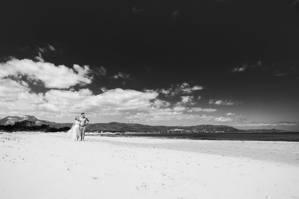 Black and white landscape of a beach with dramatic cloudy sky and coastal mountains.