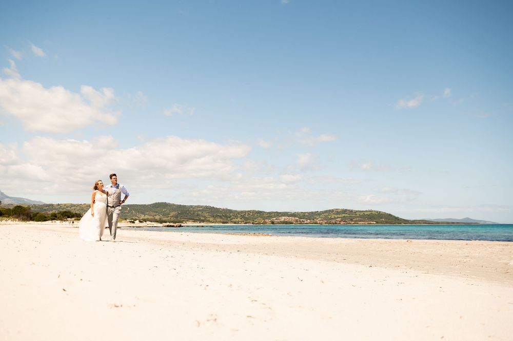 Panoramic view of a pristine beach with turquoise waters and distant mountains under blue skies.