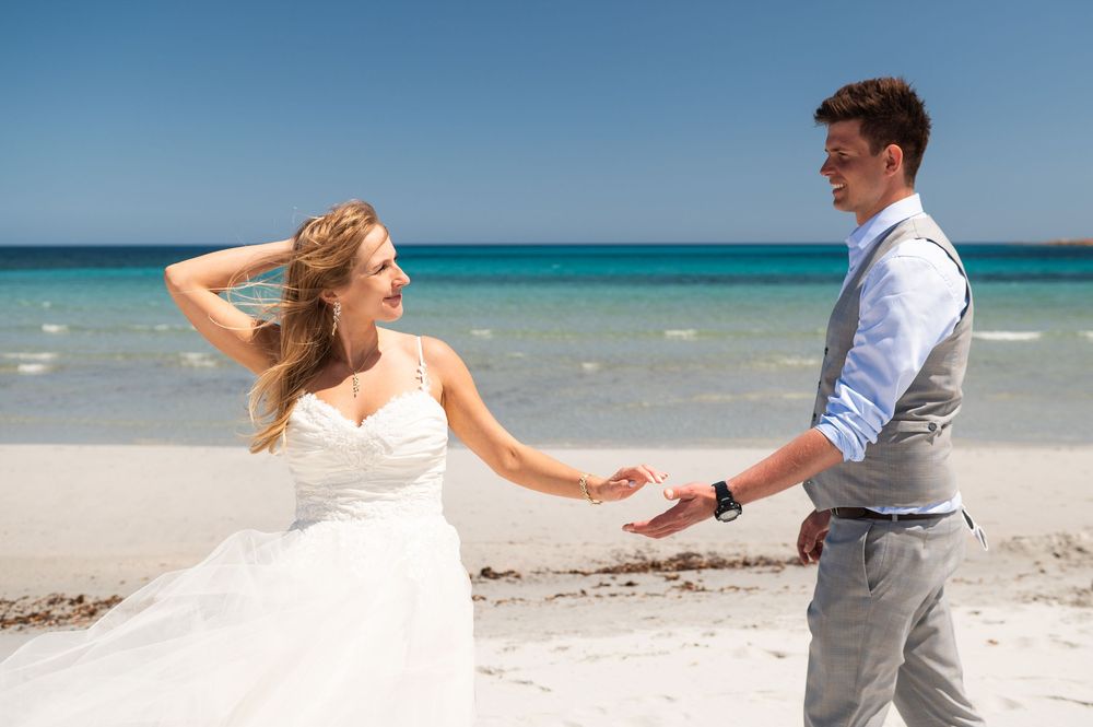 A romantic beach photoshoot sequence with a couple dancing on white sand near crystal blue waters.