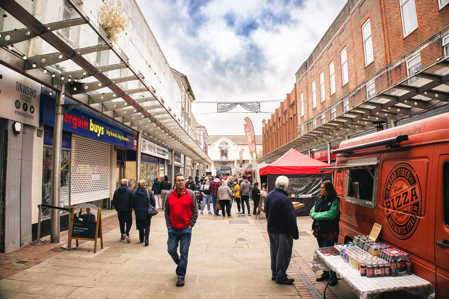 Busy street market with food stalls, vendors, and shoppers, capturing the urban community spirit and local commerce of Llanelli.