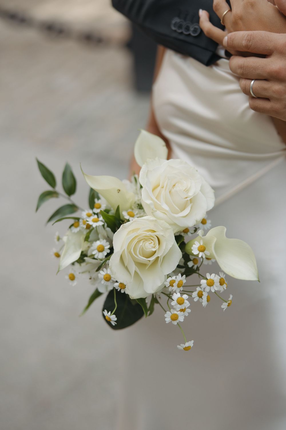 Delicate white roses and daisies in a wedding bouquet arrangement.