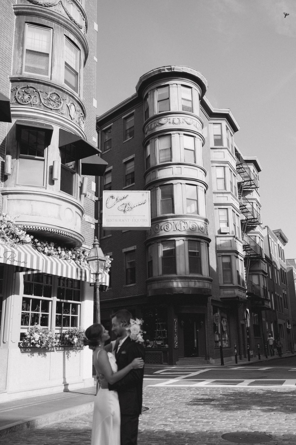 Historic Boston street corner with Victorian-style bay windows and architectural details in black and white.