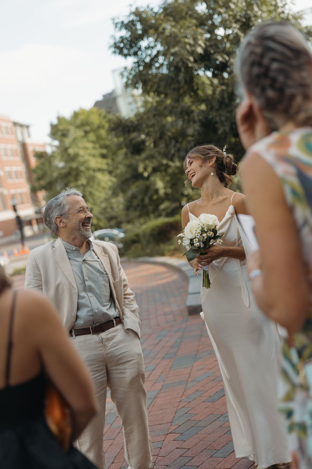 Wedding celebration on brick pavement with joyful interactions between attendees.