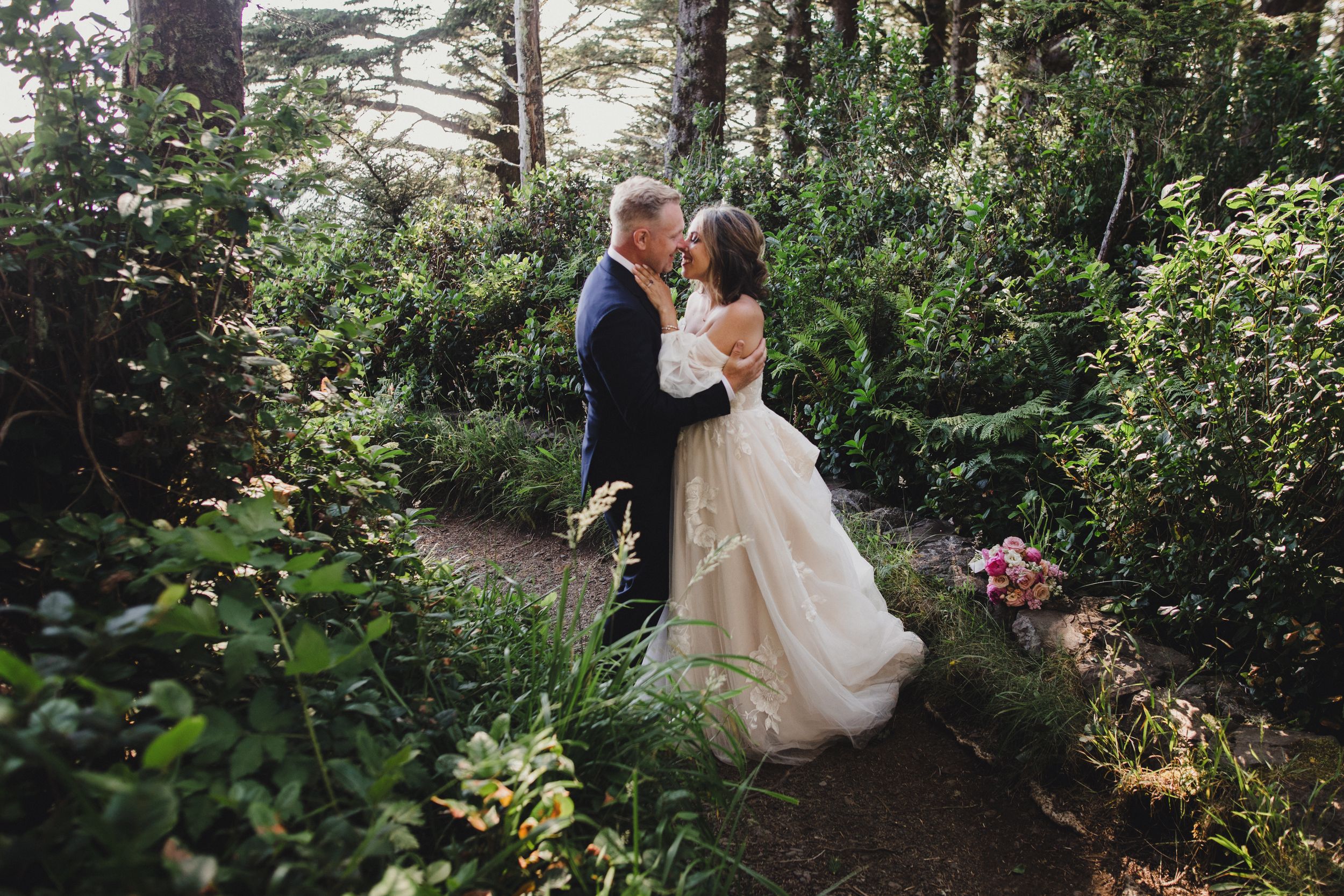 A couple shares a romantic moment in a lush garden setting surrounded by greenery and natural light.