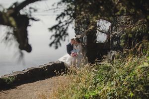 A scenic coastal pathway winds through lush greenery along the water's edge on a sunny day.