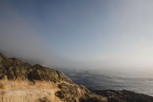 Misty coastal cliffs overlook a dramatic Pacific Northwest shoreline at sunset.