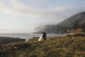 Scenic coastal landscape with misty cliffs and crashing waves along the Pacific Northwest shoreline on a foggy day.
