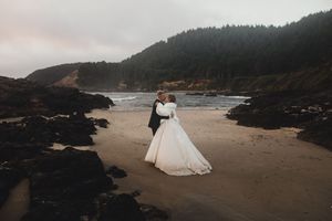A romantic coastal wedding photoshoot along the rugged Oregon coastline at sunset with dramatic cliffs and ocean waves.