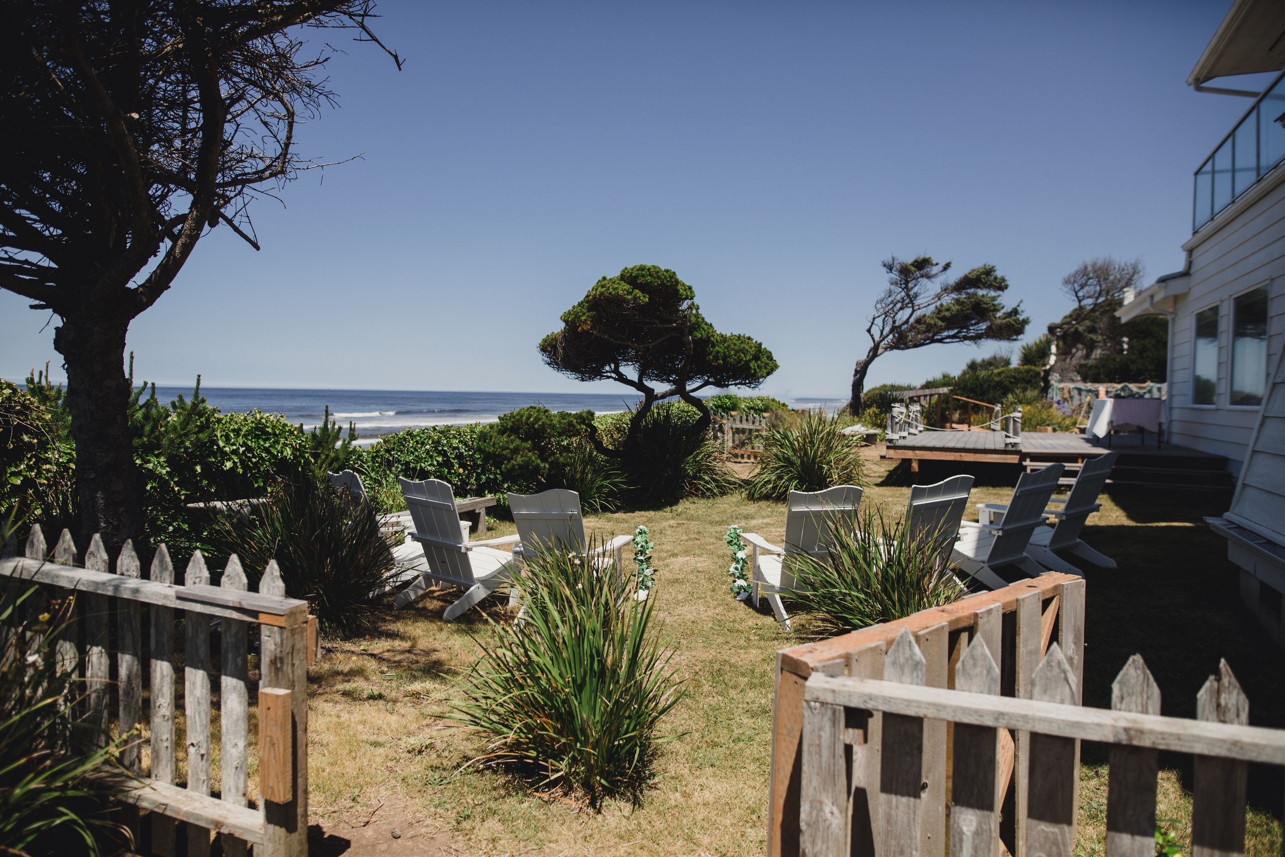 Panoramic view of a coastal property with multiple buildings and palm trees overlooking the ocean on a sunny day.