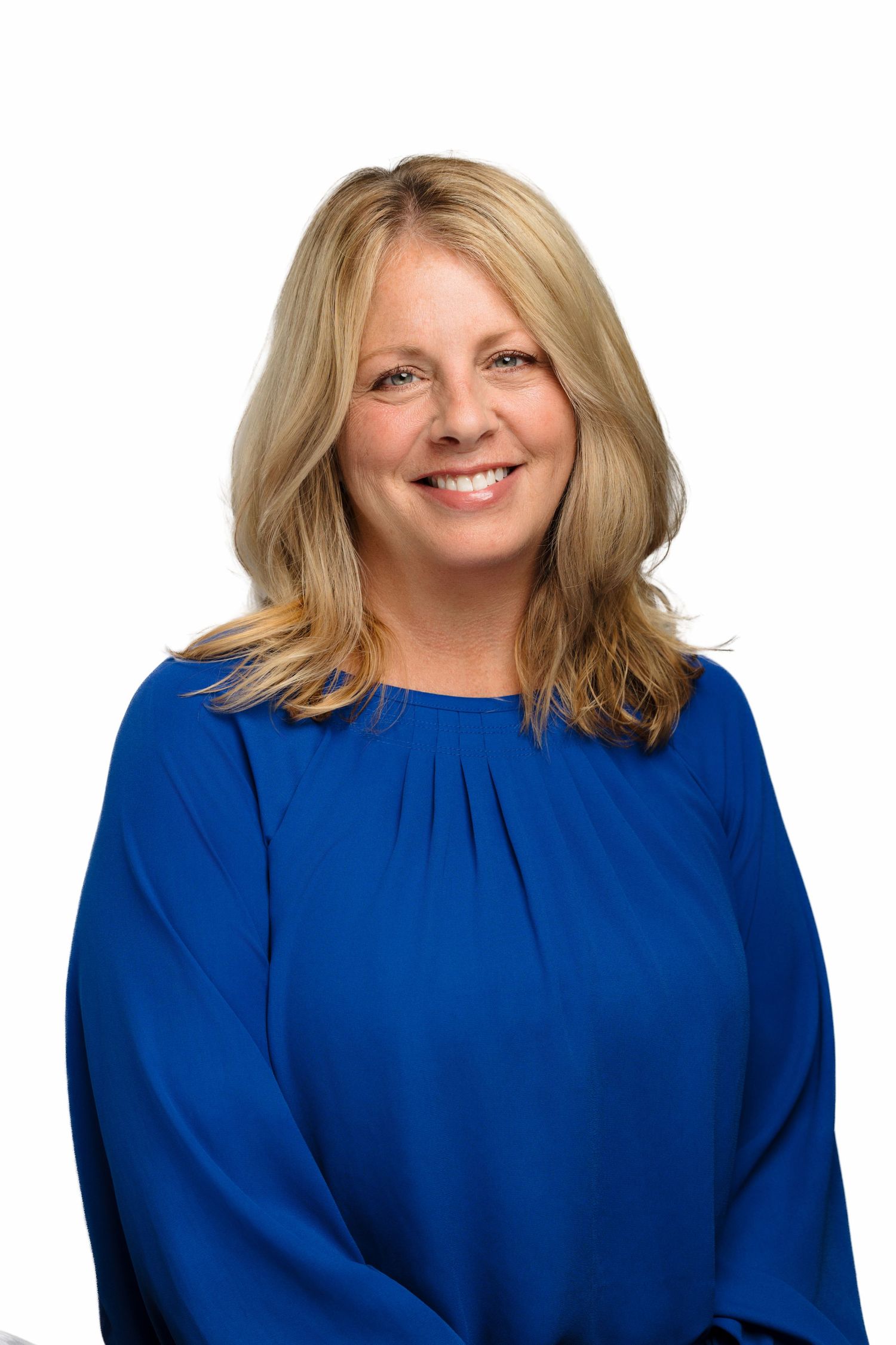 Professional headshot portrait of someone in a royal blue blouse with blonde shoulder-length hair against white background.