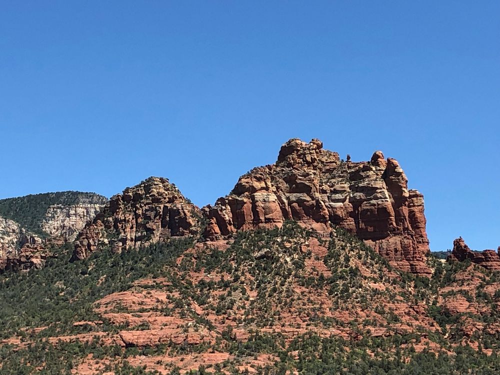 Panoramic view of red rock formations and cliffs against bright blue sky in Sedona, Arizona.