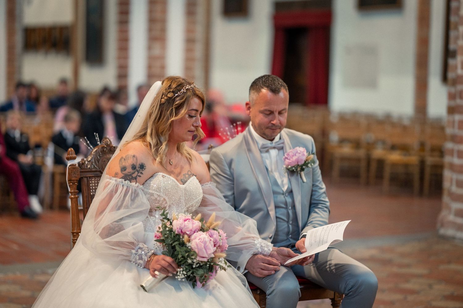 Ein formell gekleidetes Brautpaar posiert vor einem prächtigen gelben Herrenhaus mit weißen Verzierungen an ihrem Hochzeitstag.