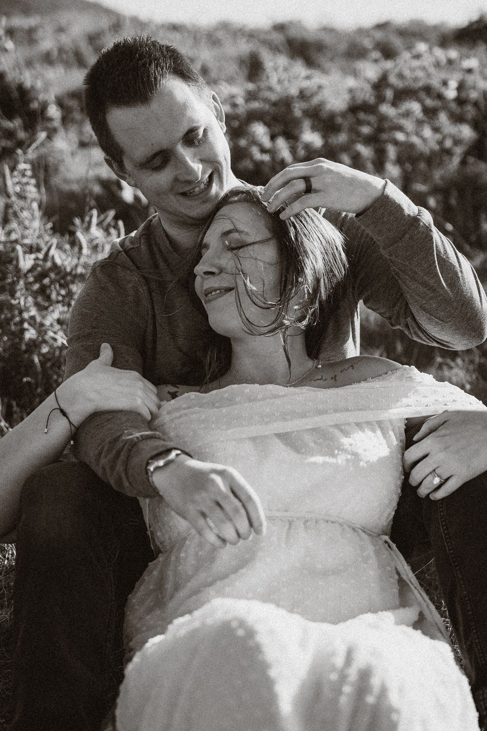 An intimate black and white portrait showing tender moments between a couple outdoors.