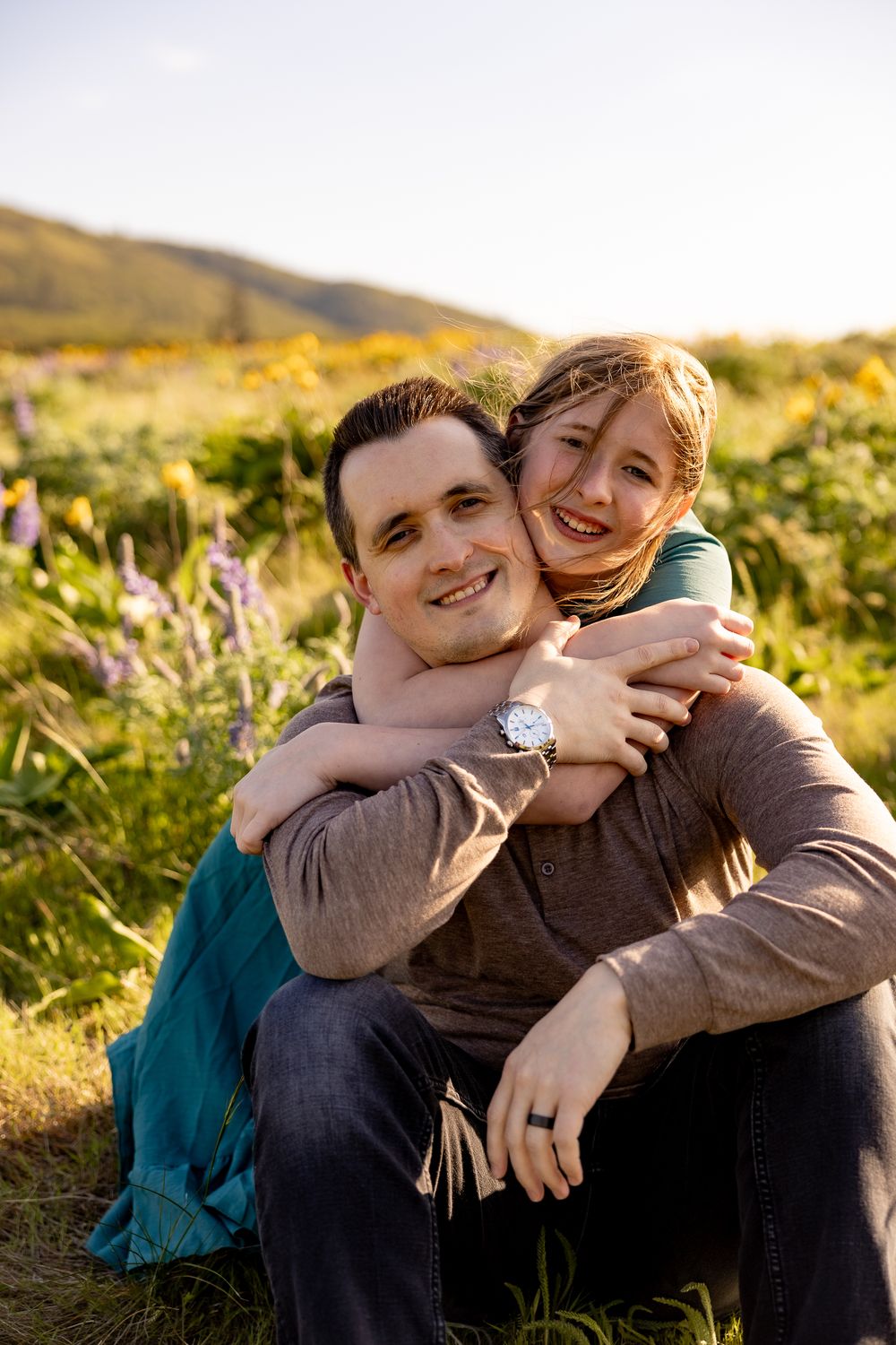 A joyful embrace captured in a field of wildflowers during sunset.