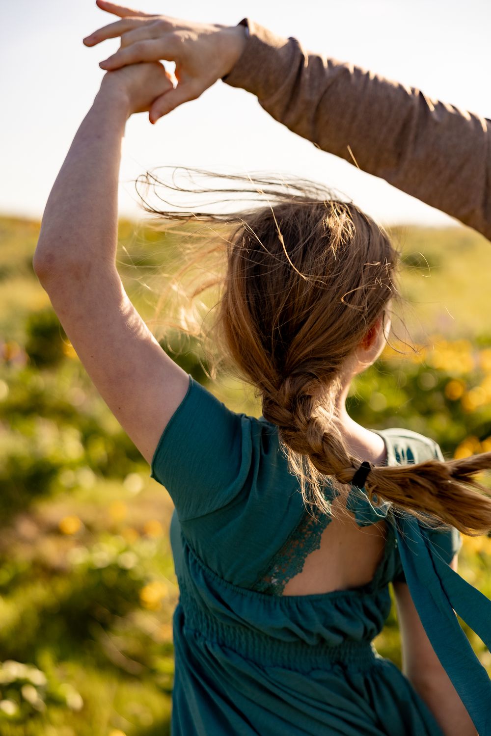 A silhouette of someone dancing with flowing hair against a golden sunset in a wildflower field.