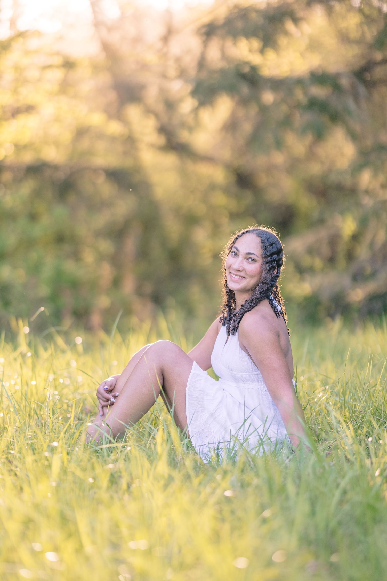 Child laying in sunlit grass during outdoor portrait session.