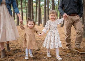 Children's feet in casual shoes stand on a dirt forest path during a family photo session.
