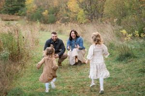 A group enjoys a playful autumn day running through a grassy meadow surrounded by fall foliage.