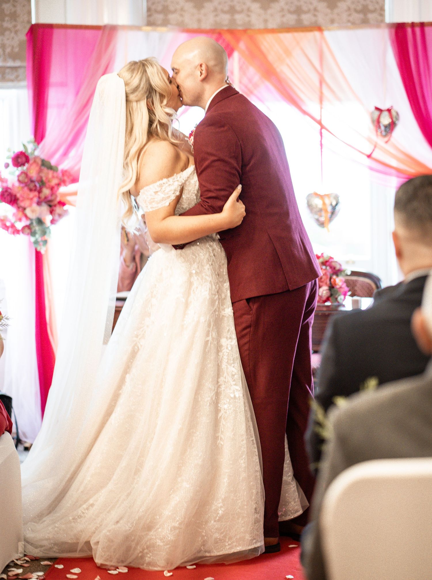A romantic first dance moment at a wedding reception with pink drapery and decor in the background.