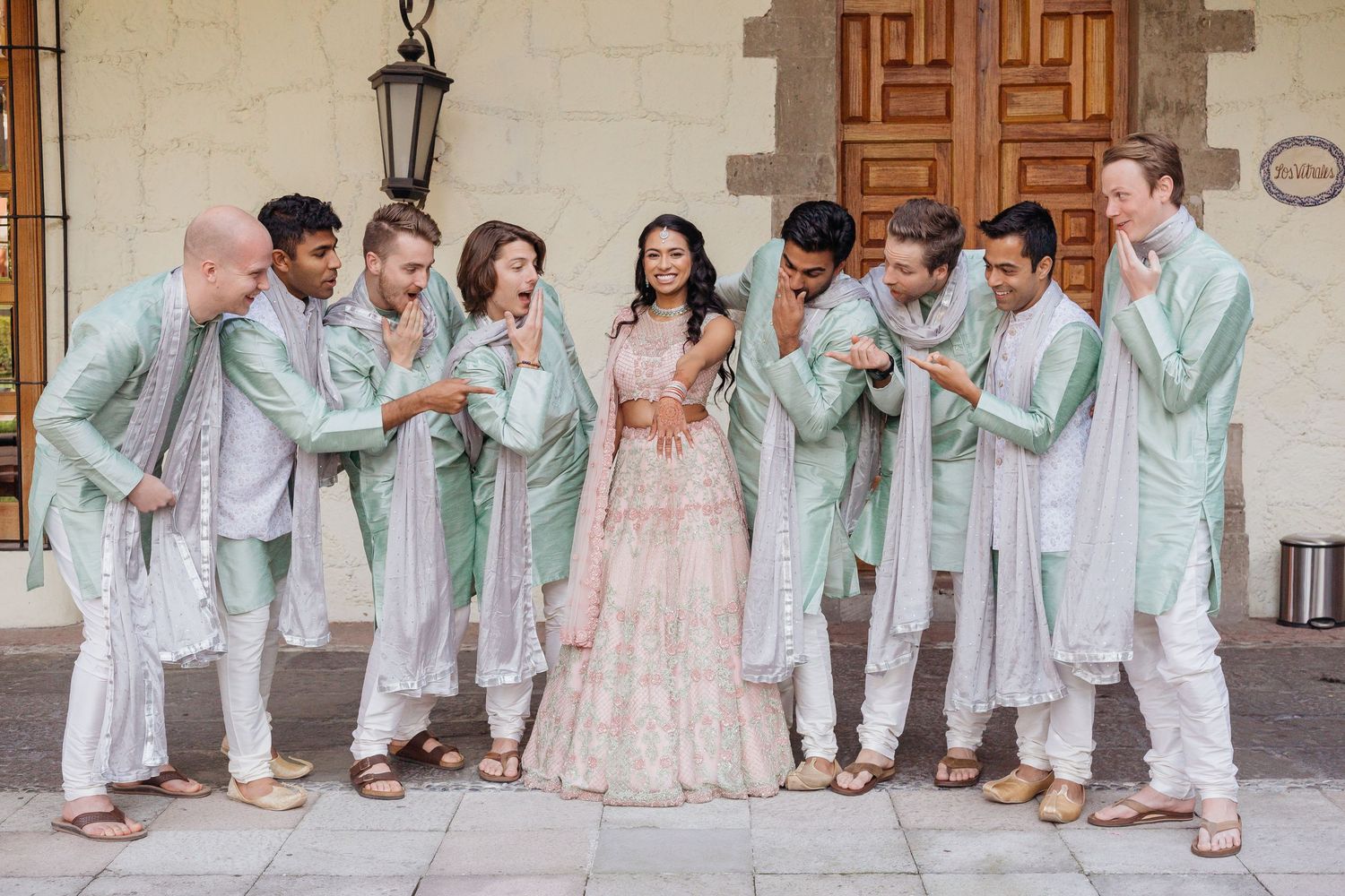 Wedding party wearing coordinated mint green and pink outfits posing together outdoors.