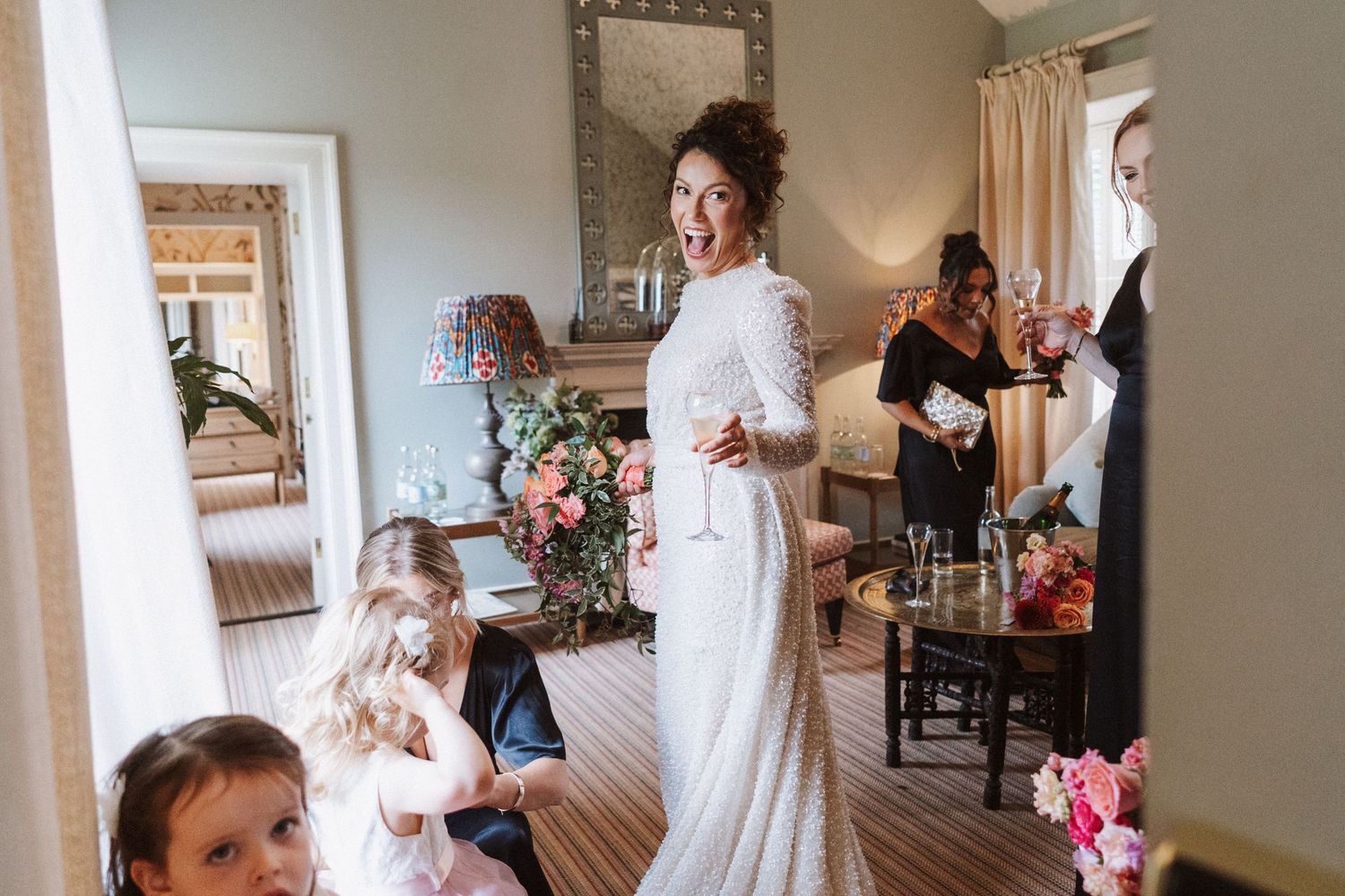 Wedding preparations in a light-filled room with elegant decor and flowing white dress details.