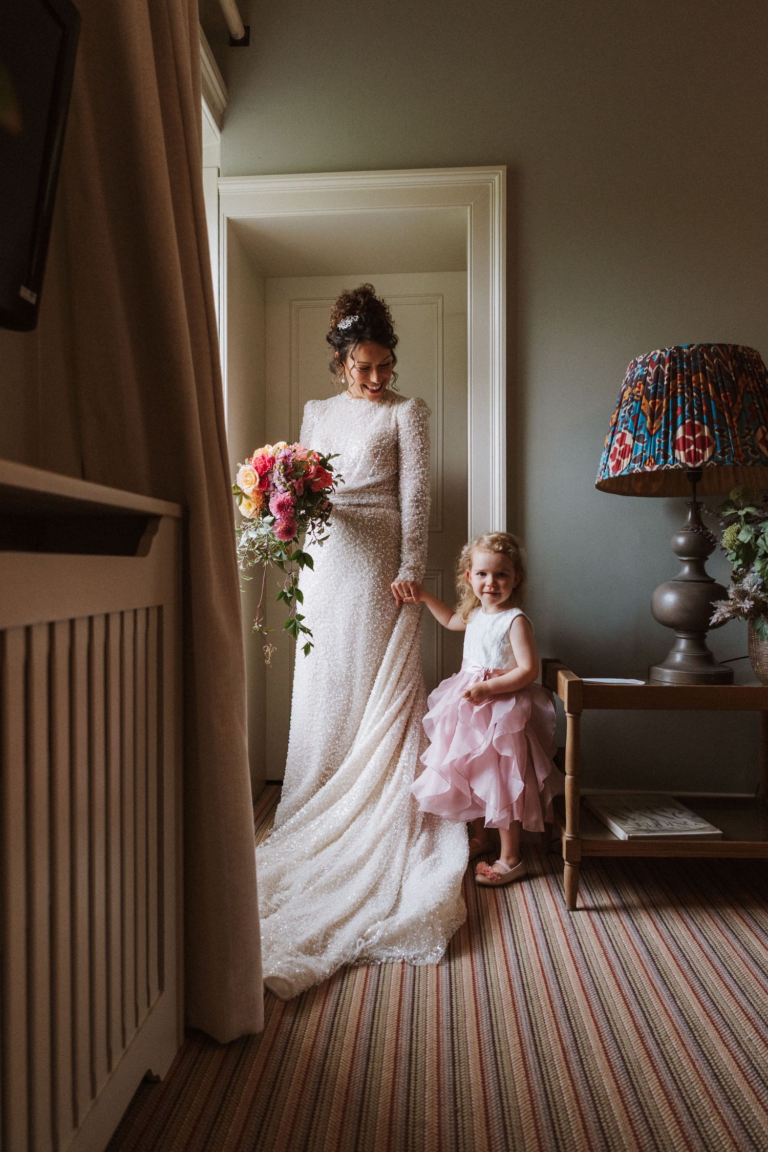 A sequence of tender moments between a bride in a lace gown and a small child in a pink dress by a window.