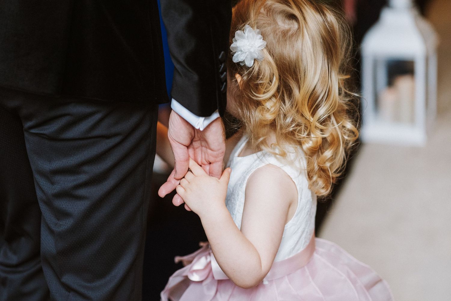 A toddler in a pink dress laughs and plays during a formal event.