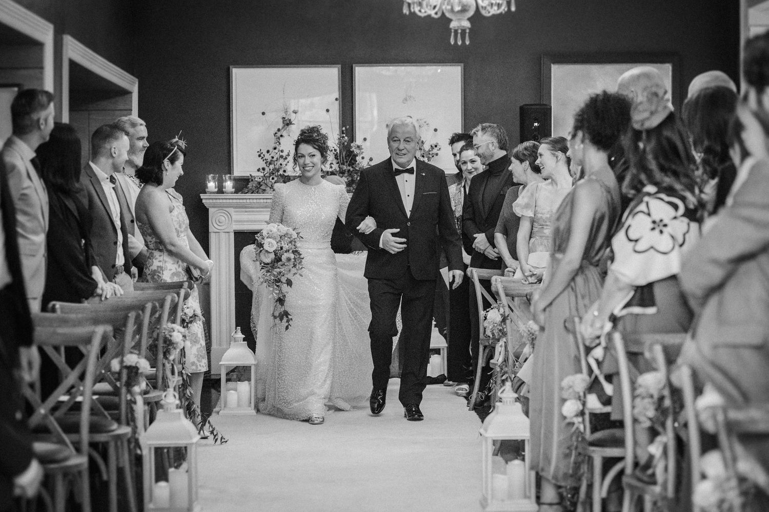 Black and white photo of wedding guests dancing and celebrating on a dance floor at a reception party.
