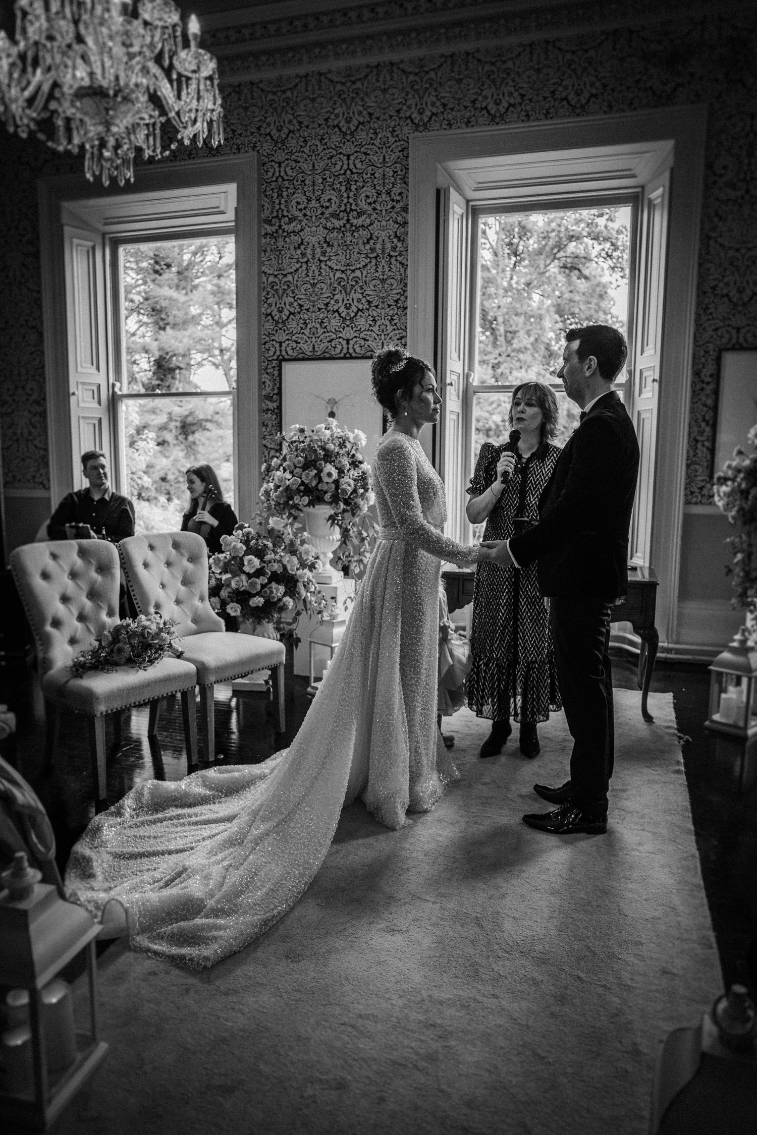 Black and white wedding ceremony photos showing elegant interior with chandelier and gathered guests.