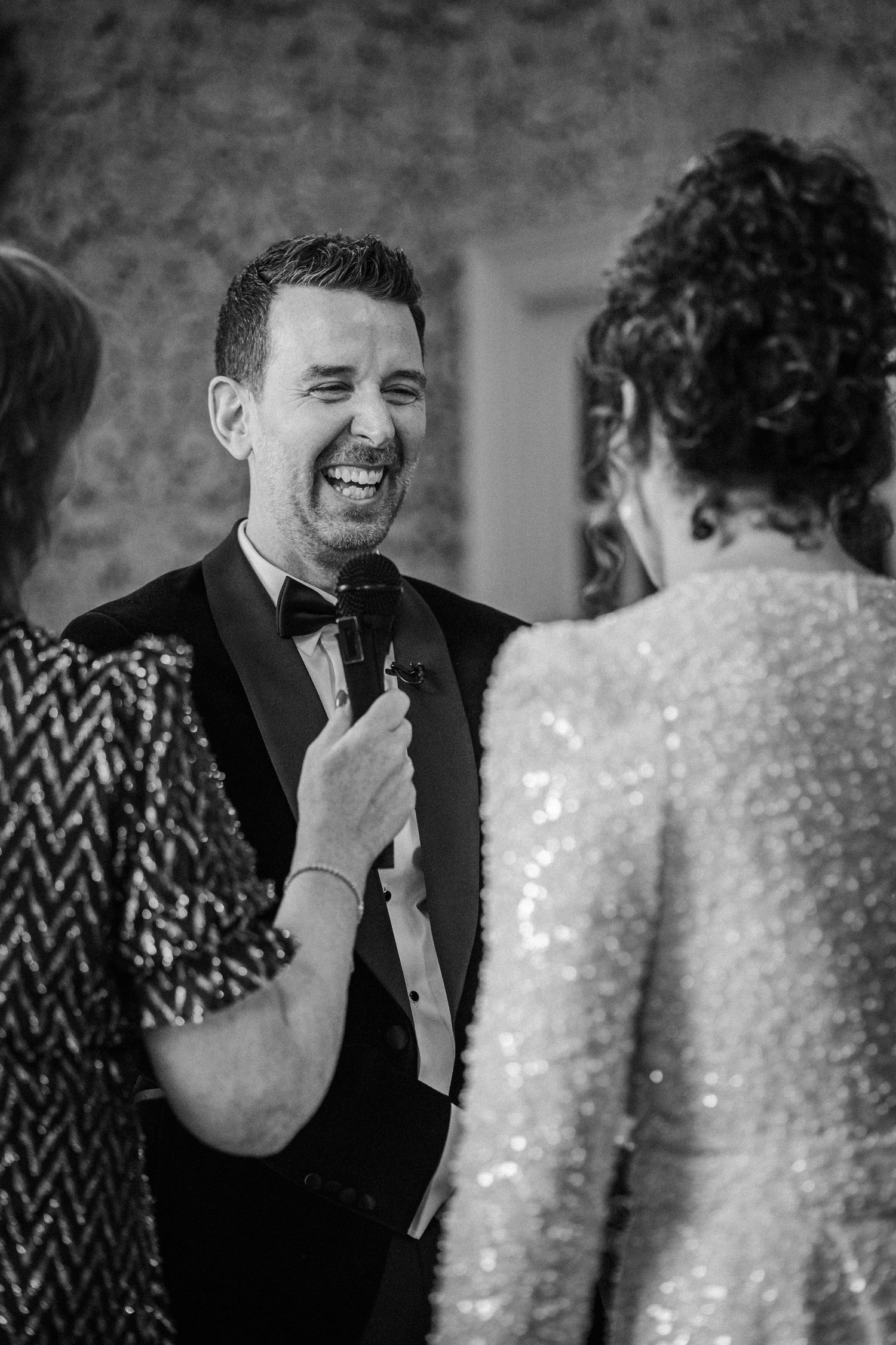 A candid black and white moment of laughter and joy during a formal event.