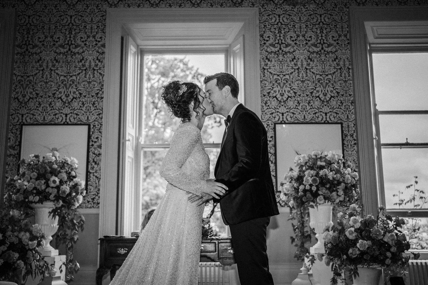 Intimate wedding moments captured in a vintage-styled room with damask wallpaper and natural lighting.