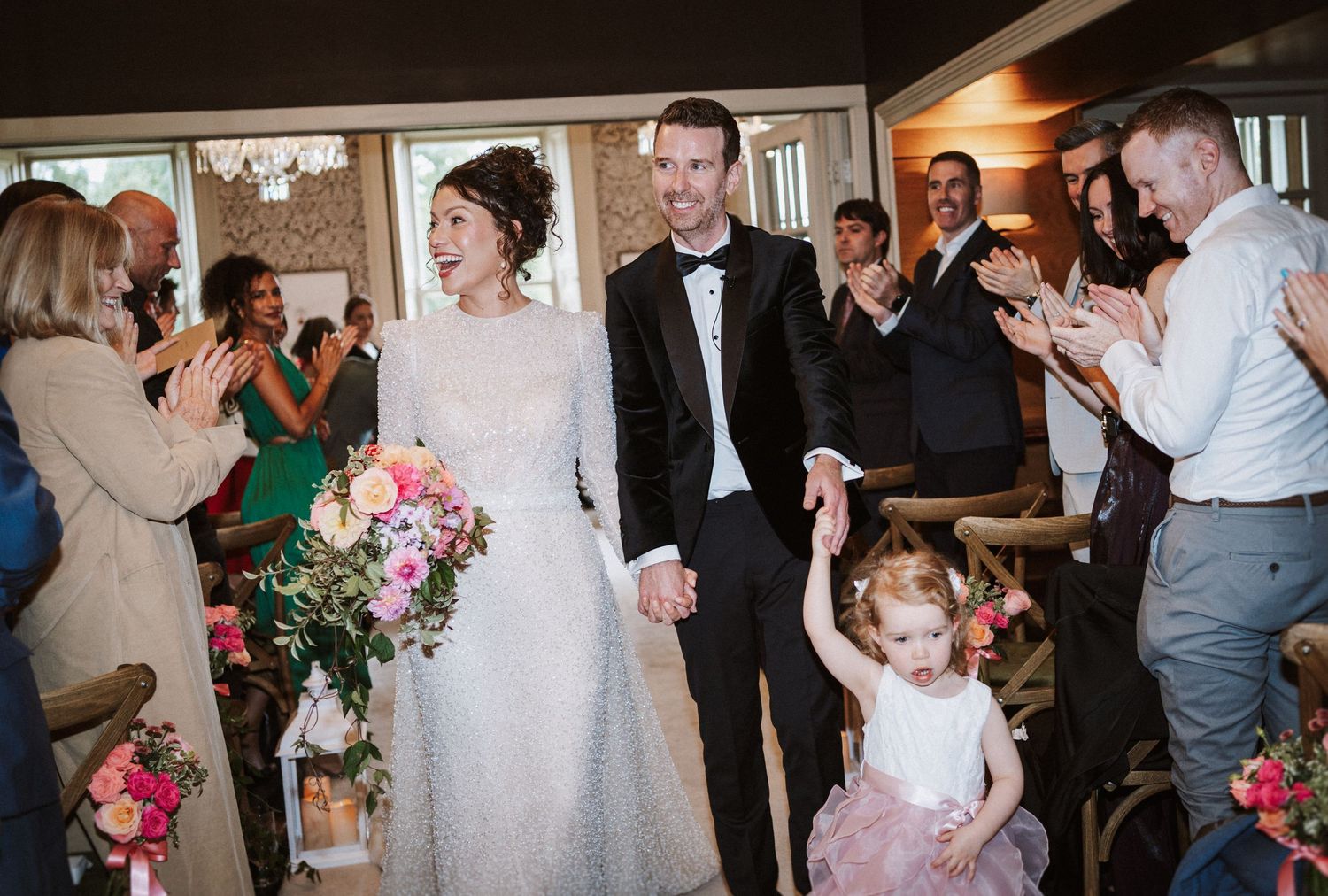 Wedding party celebration with guests dancing and socializing in an indoor venue with festive atmosphere.