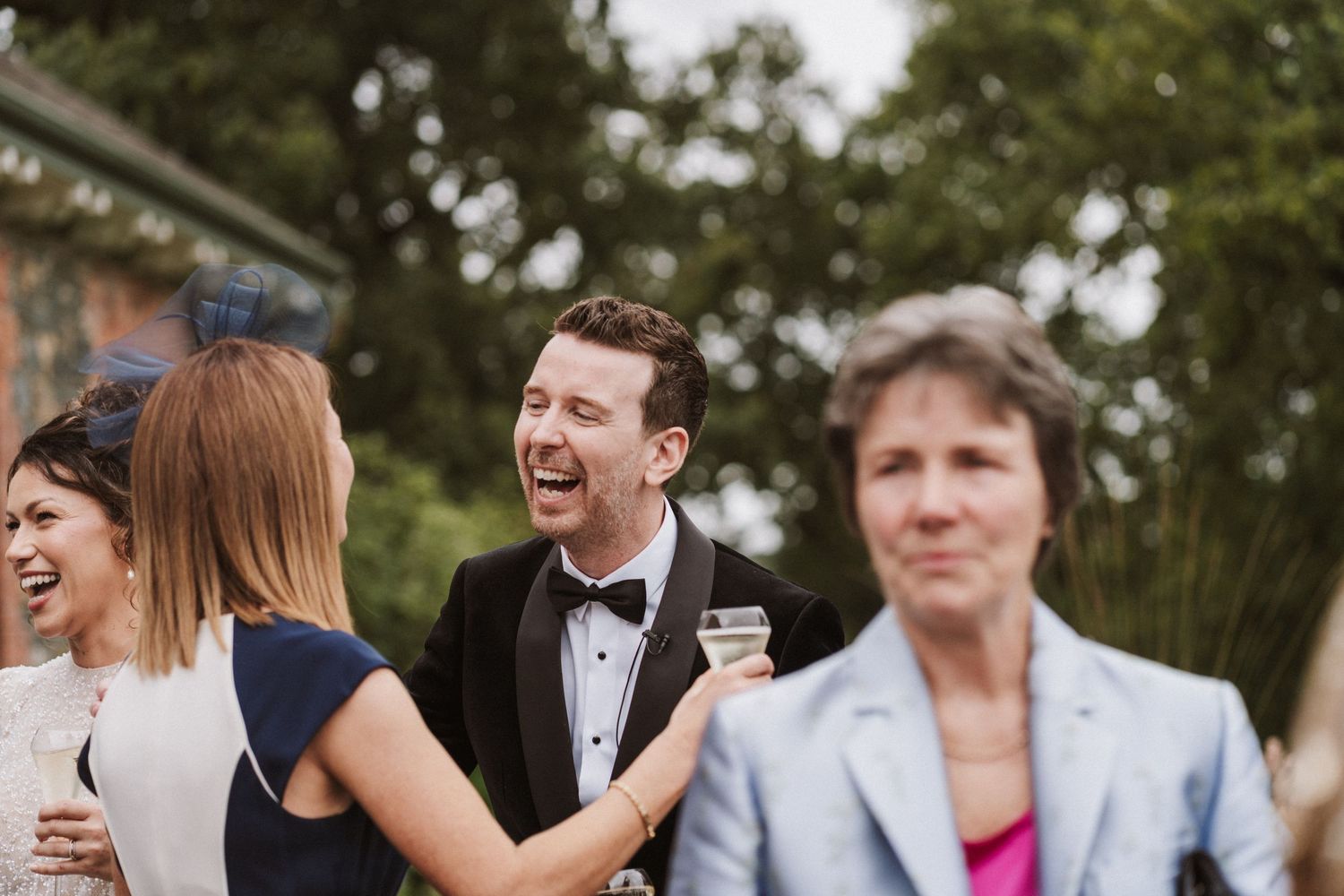 A candid moment of laughter and conversation at an outdoor wedding reception.