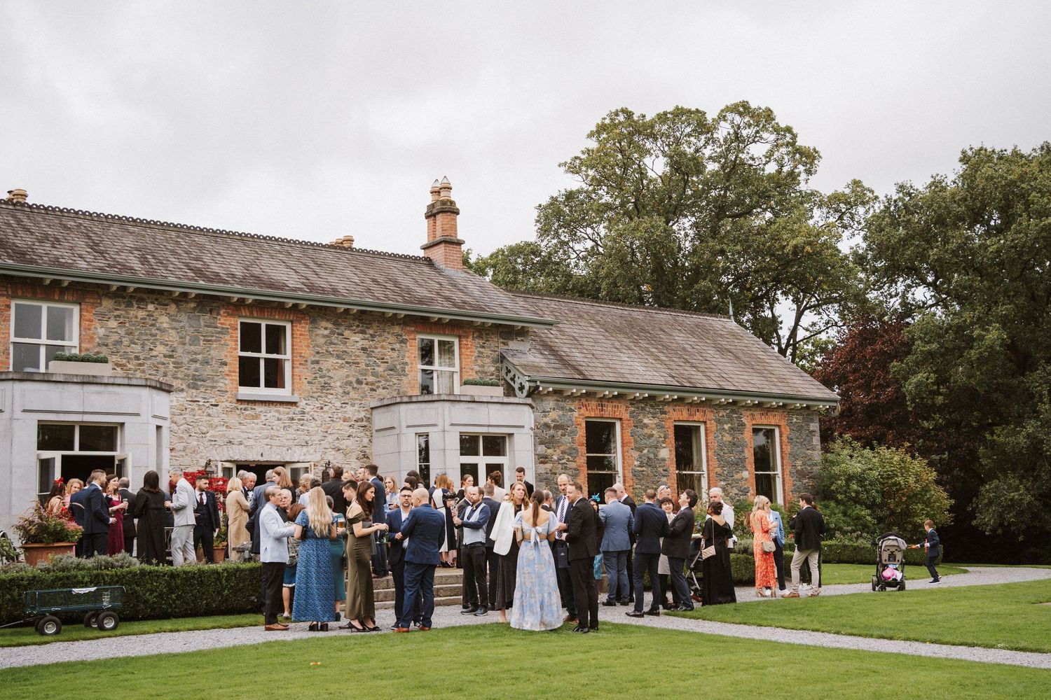 Wedding guests gather outside a rustic stone cottage for a countryside celebration.
