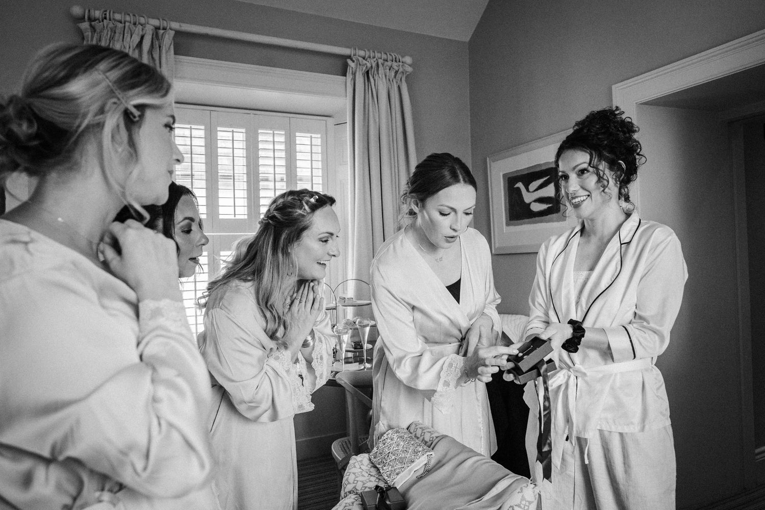 A sequence of black and white photos showing wedding preparation moments with bridesmaids getting ready in robes.