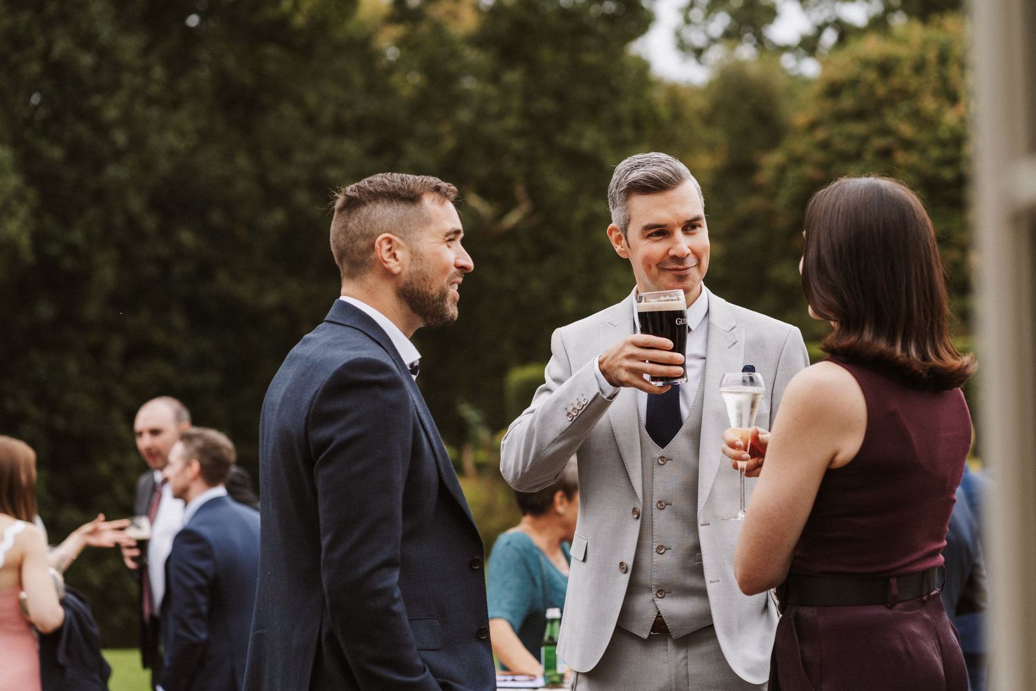 Wedding guests mingle and socialize at an elegant outdoor garden party.