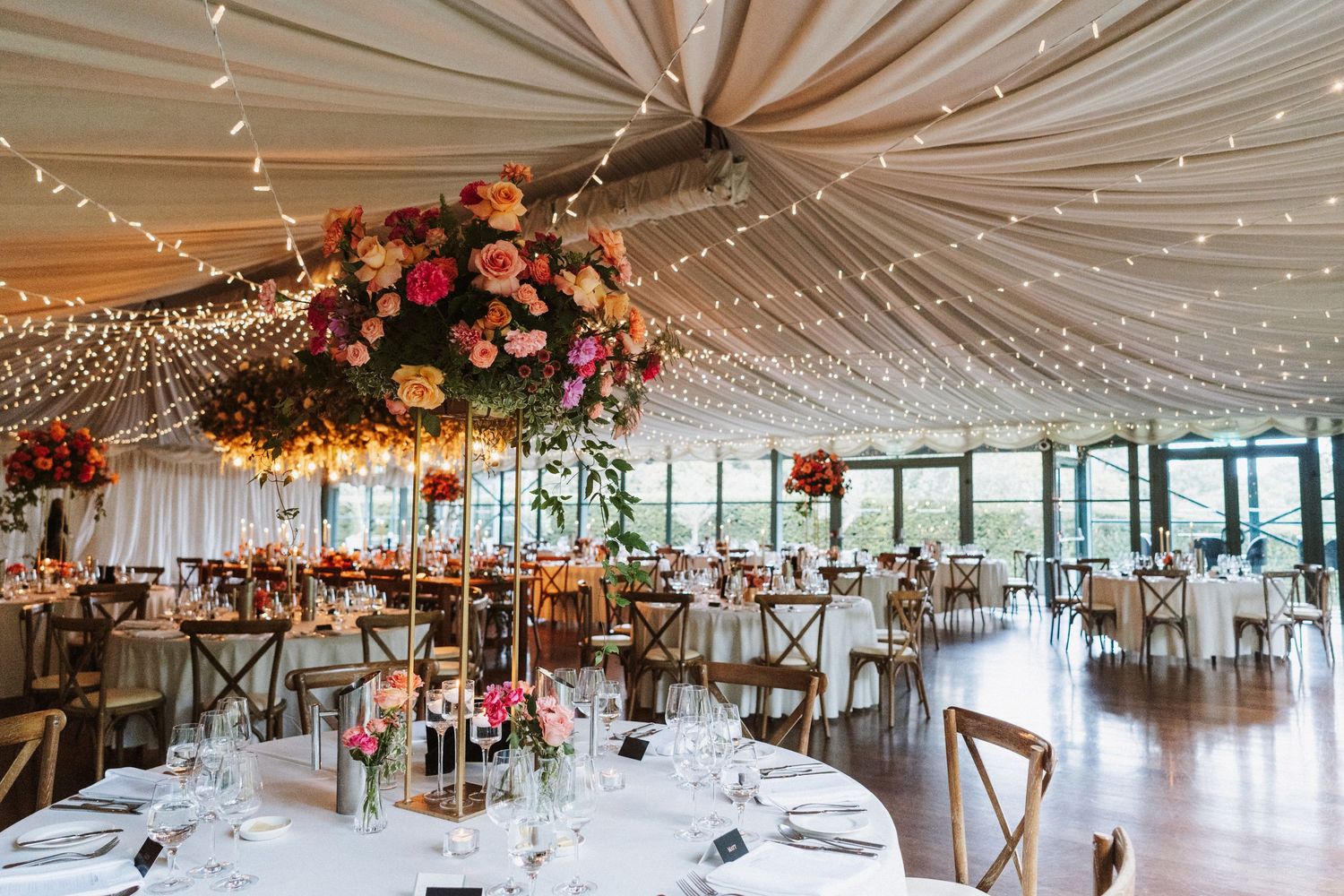 Elegant wedding reception venue with draped fabric ceiling and string lights creating a romantic atmosphere.