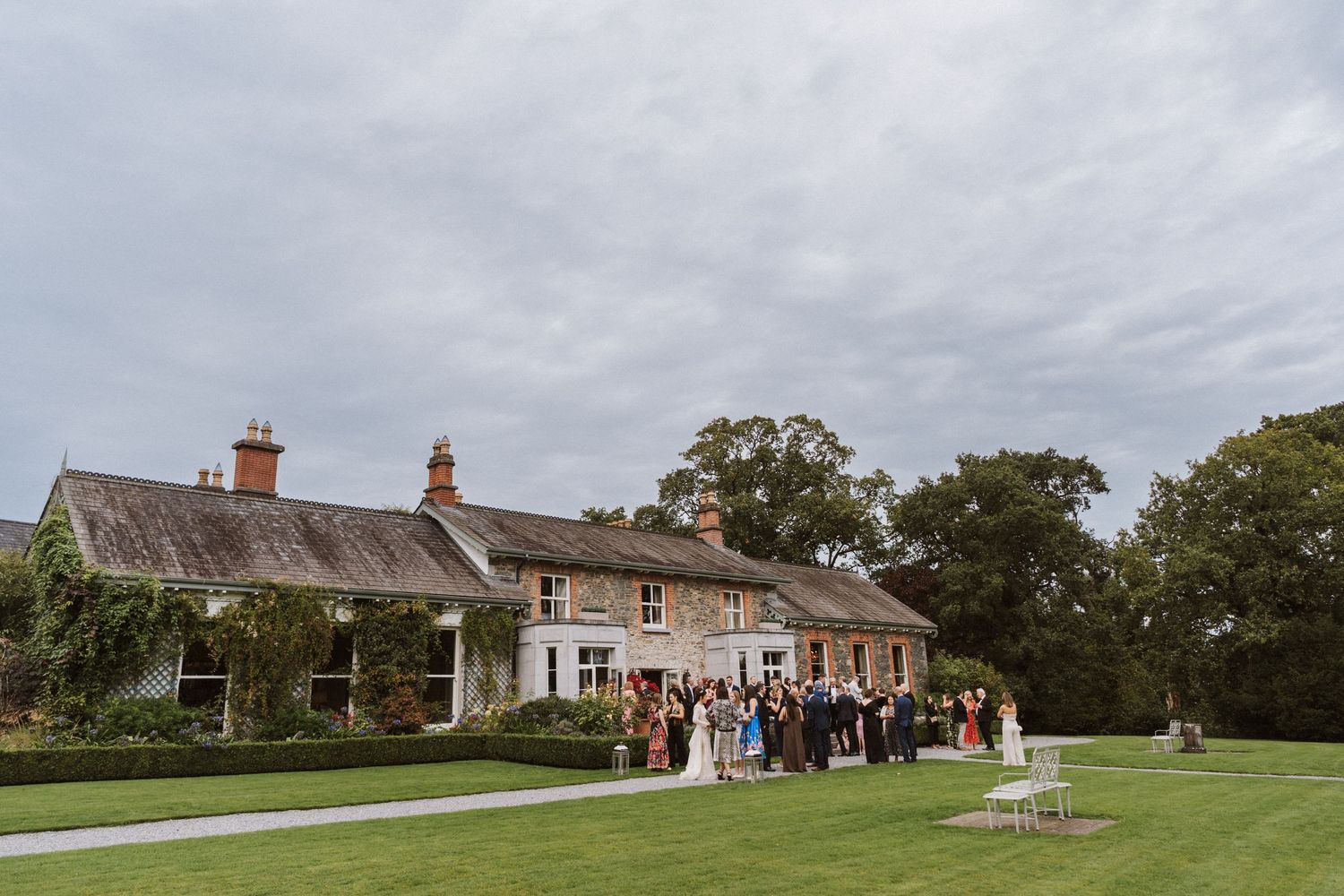 Panoramic view of a rustic countryside wedding venue with stone buildings and expansive green lawns.
