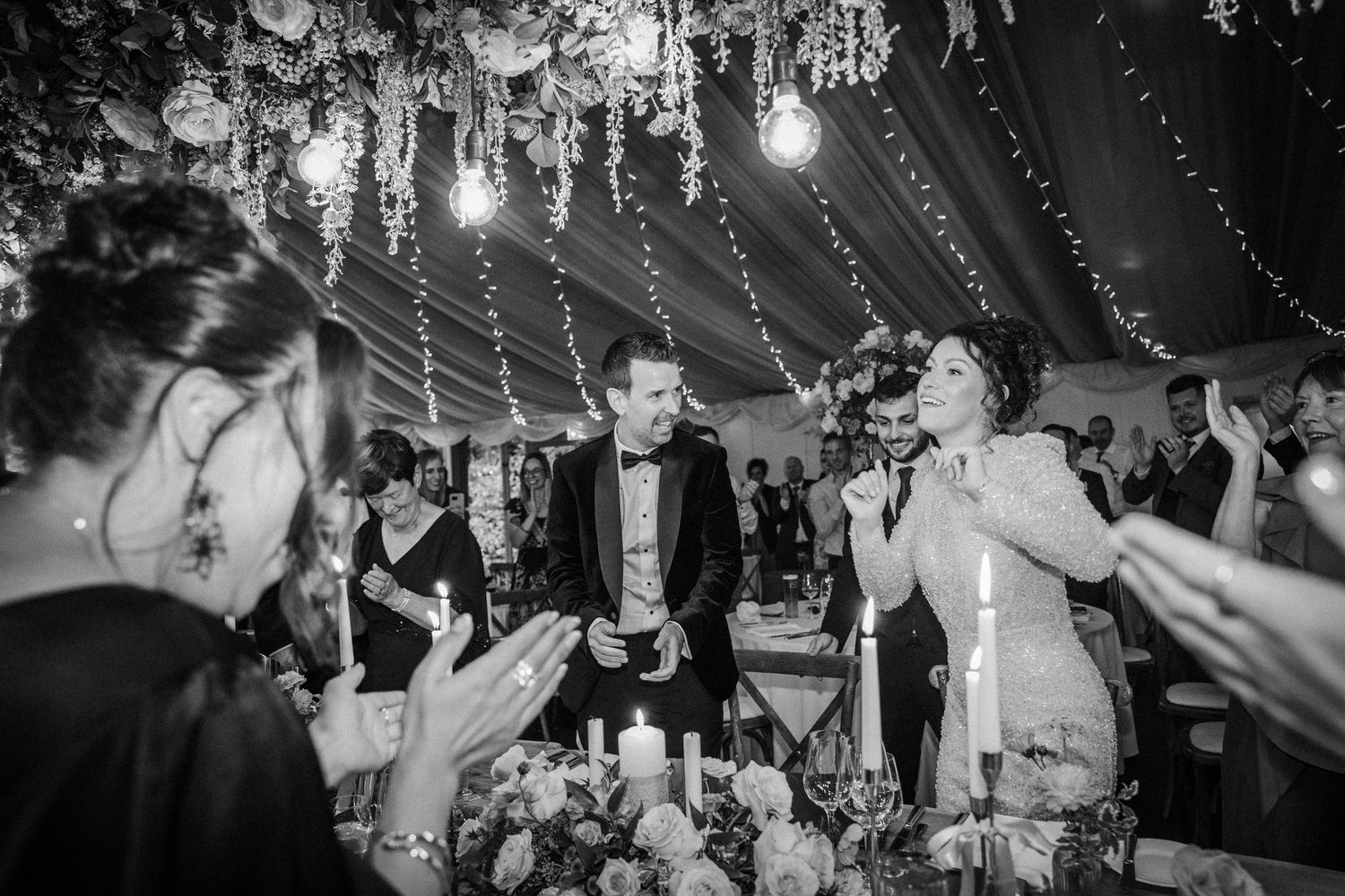 Wedding reception guests dancing and celebrating on a crowded dance floor under ambient lighting.