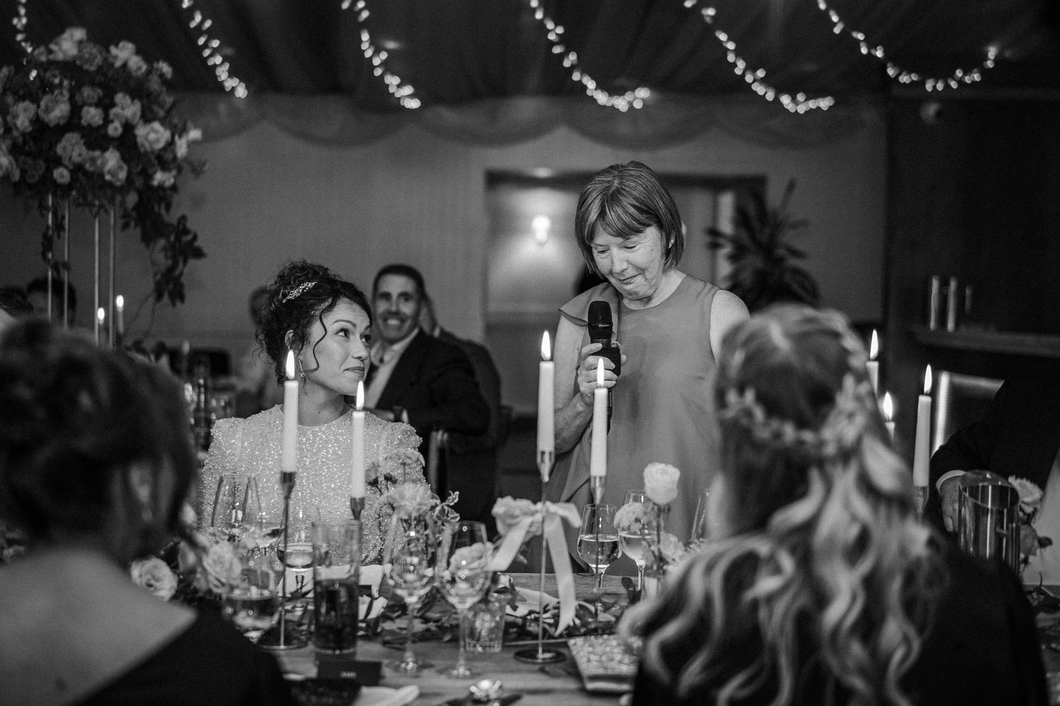 Black and white photo of a wedding reception venue decorated with string lights and garlands.